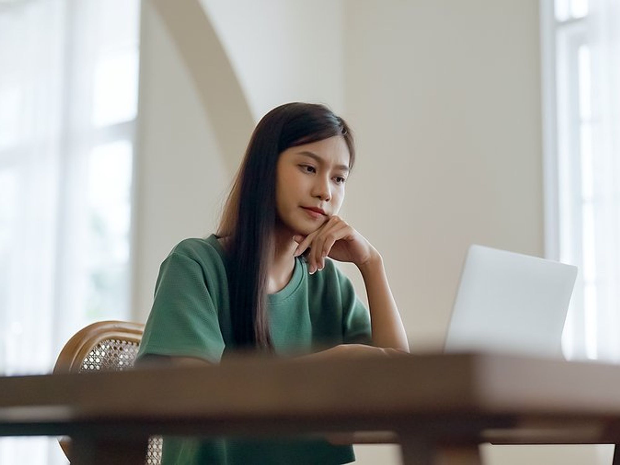 Young woman / recent college grad on laptop considering factors before accepting first job