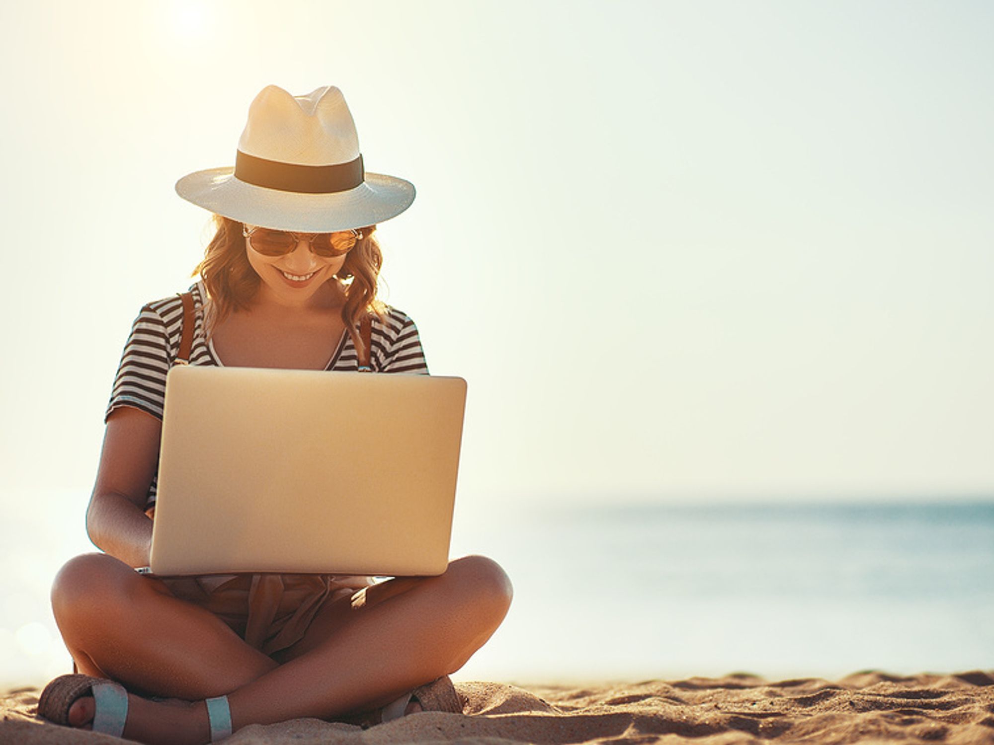 Young woman works on her resume while on the beach.