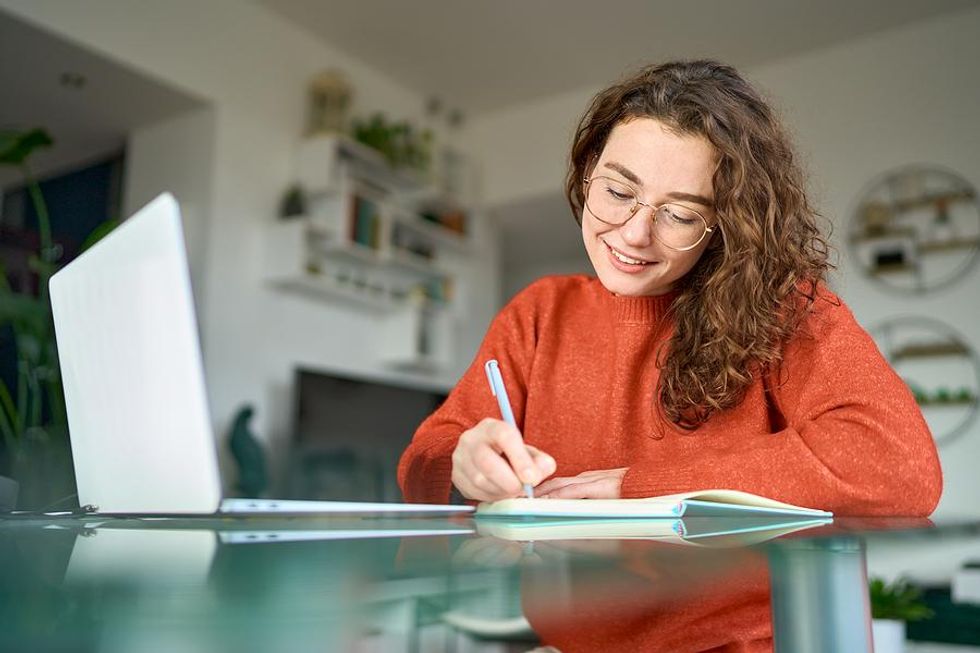 Young woman writes down her five-year plan / career goals