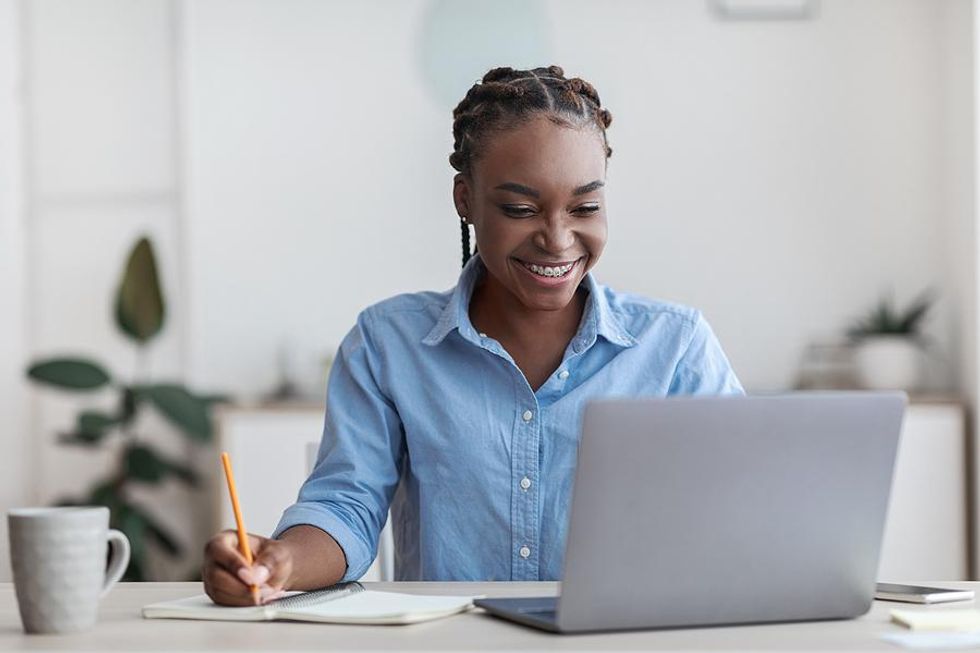 Young woman writes something down while researching companies for her proactive job search