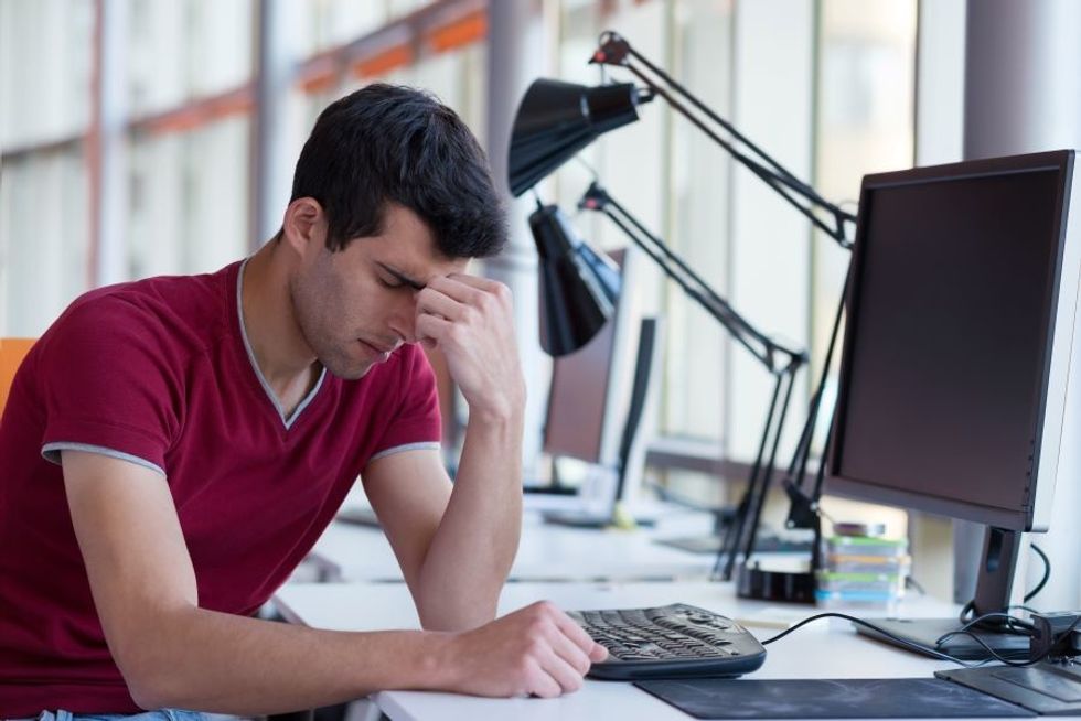 Young worker at desk feeling overwhelmed with his workload